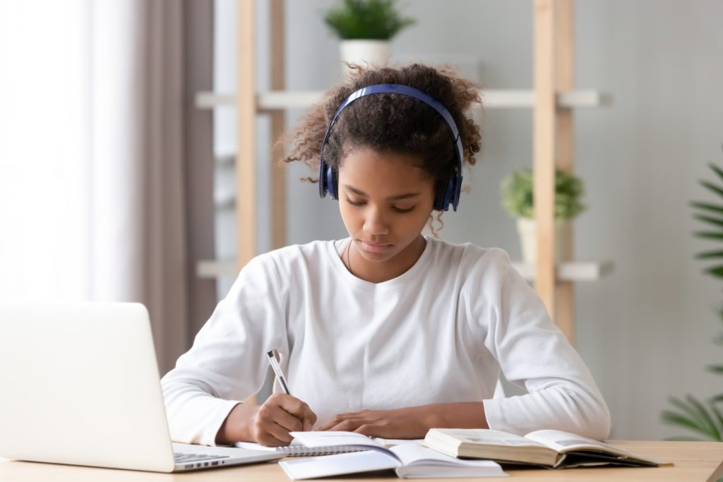 Focused,African,American,Teenage,Girl,Wearing,Headphones,Writing,Notes,Study