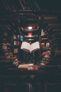 Ac ollection of books in a circular format with one open book levitating in the centre.