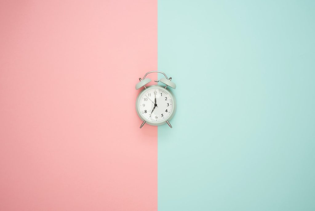 A clock with half pink and half blue background