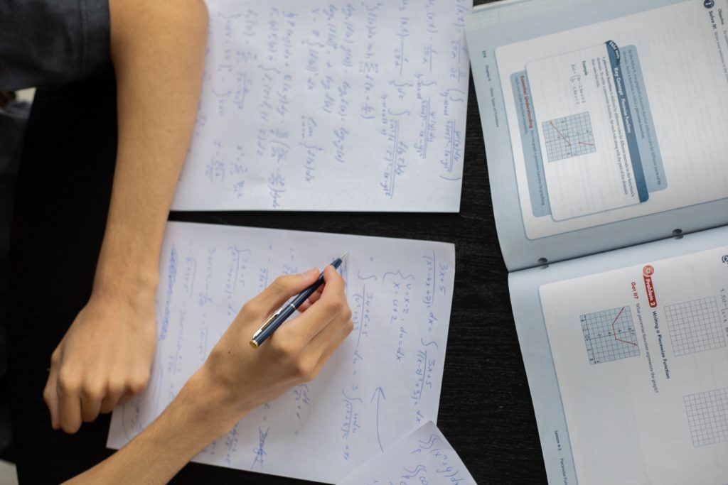 open notebook and textbook on table with person taking smart notes