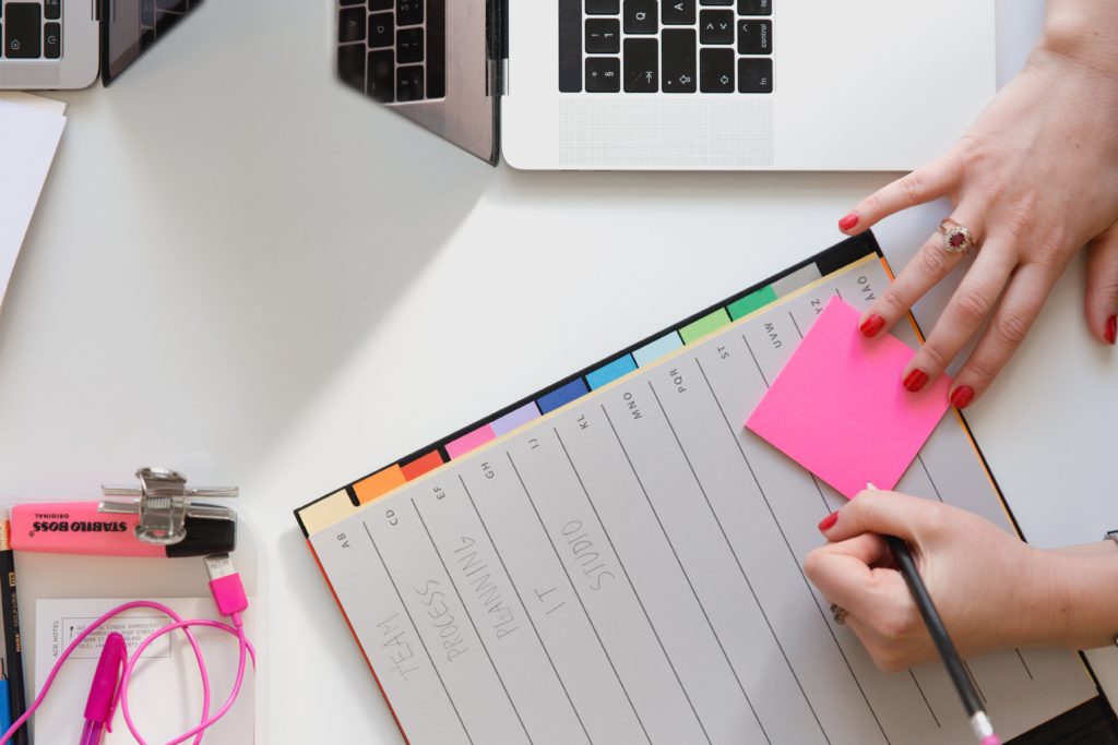 note pad next to laptop with different colours and post-it notes