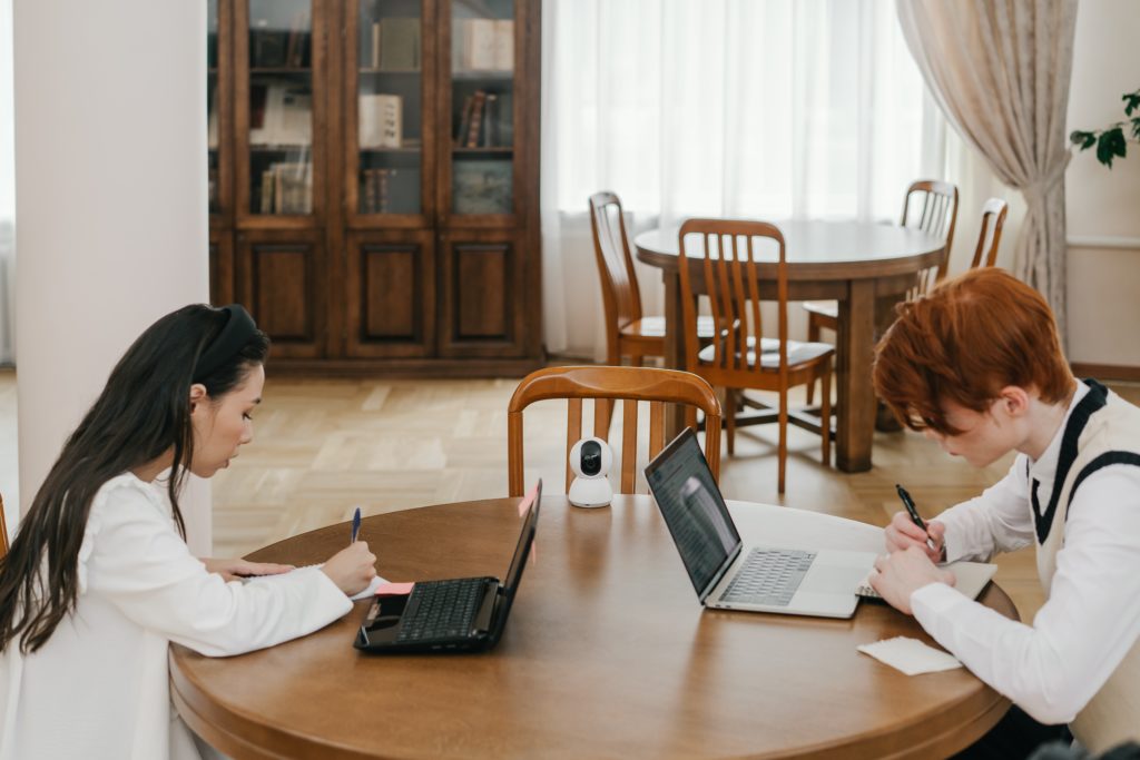 female and male student sat a table with laptops open