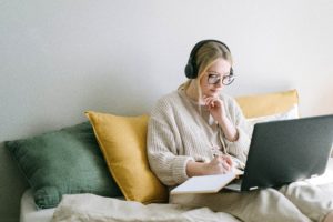 lady on sofa with laptop and headphones using free equipment for deaf or hard of hearing students