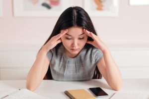 anxious female student sat at desk with notebook