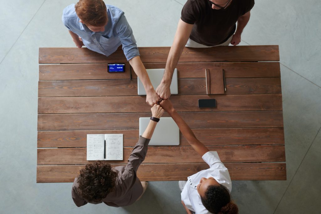 team of employees put first together over a meeting table