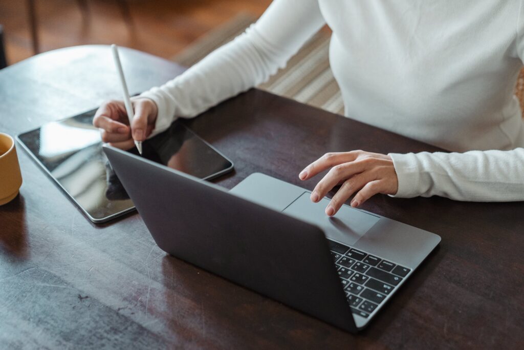 student taking automated notes at table with notebook and laptop